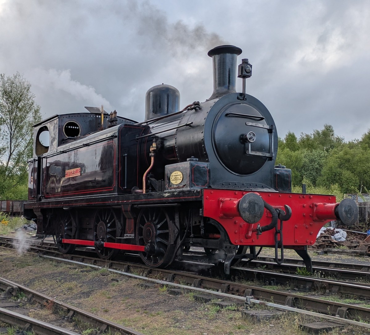 Twizell Black steam locomotive on tracks with cloudy sky in background.